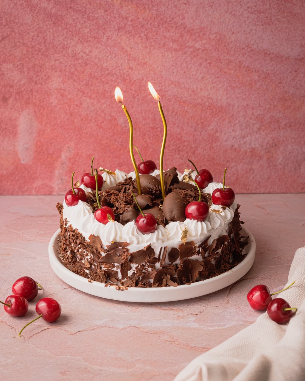 Black Forest cake with cherries and two lit candles